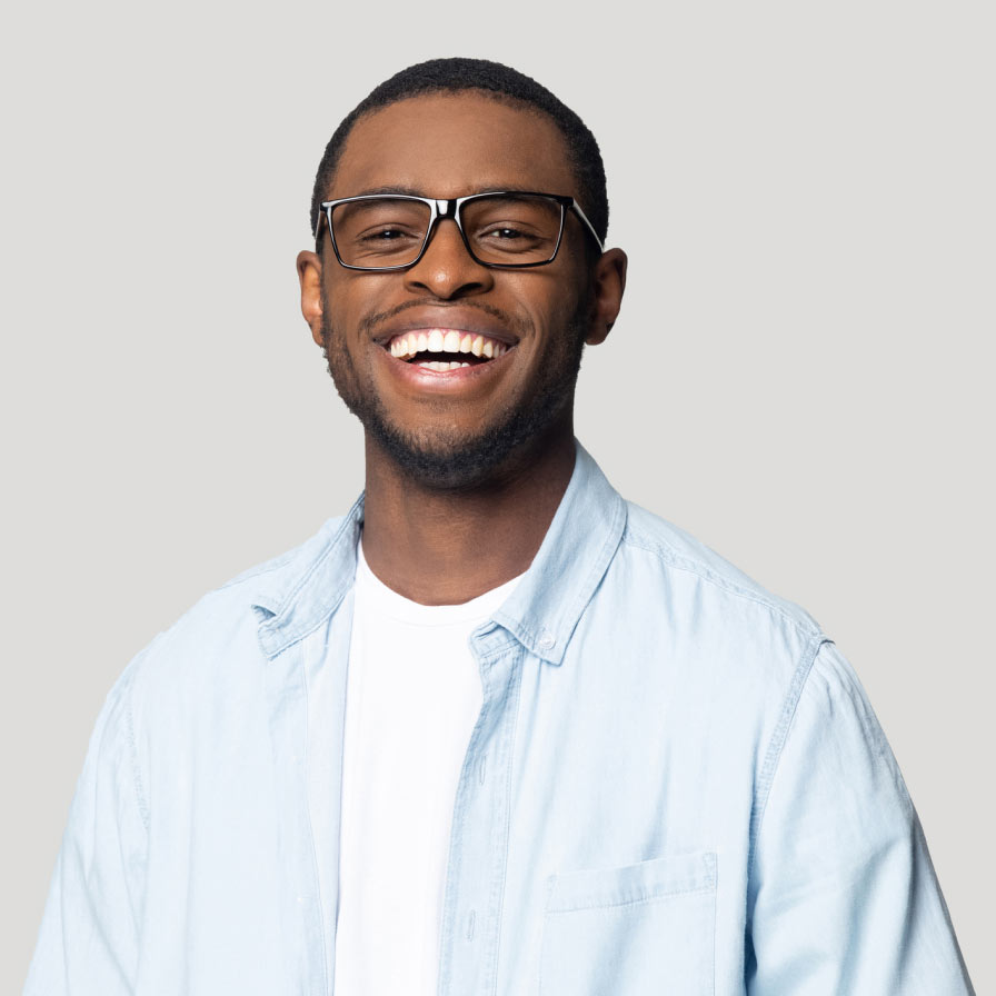 Man wearing glasses, white t-shirt and blue butotn down shirt smiling.